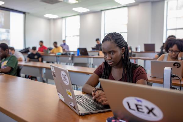 UK student sitting in classroom looking at a laptop screen 