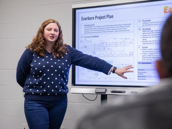 Student in front of a TV giving a presentation.
