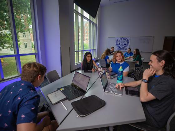 Students around a table studying in a dorm classroom
