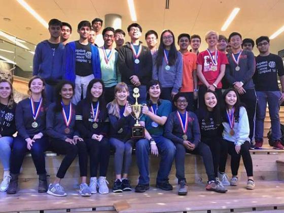 Students on "The Steps" in the Gatton student center, holding a trophy and wearing medals.
