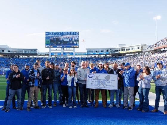 Group of People on football field with big check